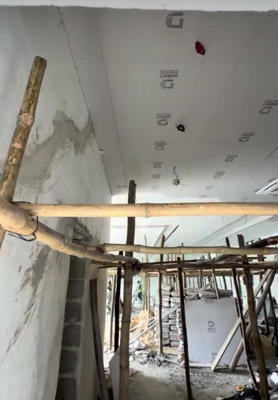 Scaffolding under a freshly boarded gypsum ceiling, cement bags stacked