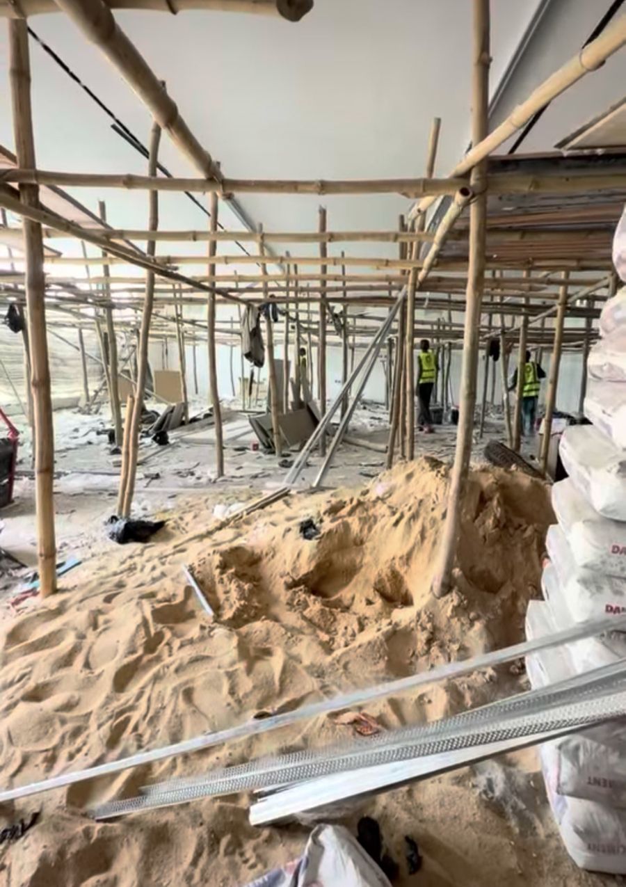 Open floor with bamboo scaffolding, sand and cement bags on day one