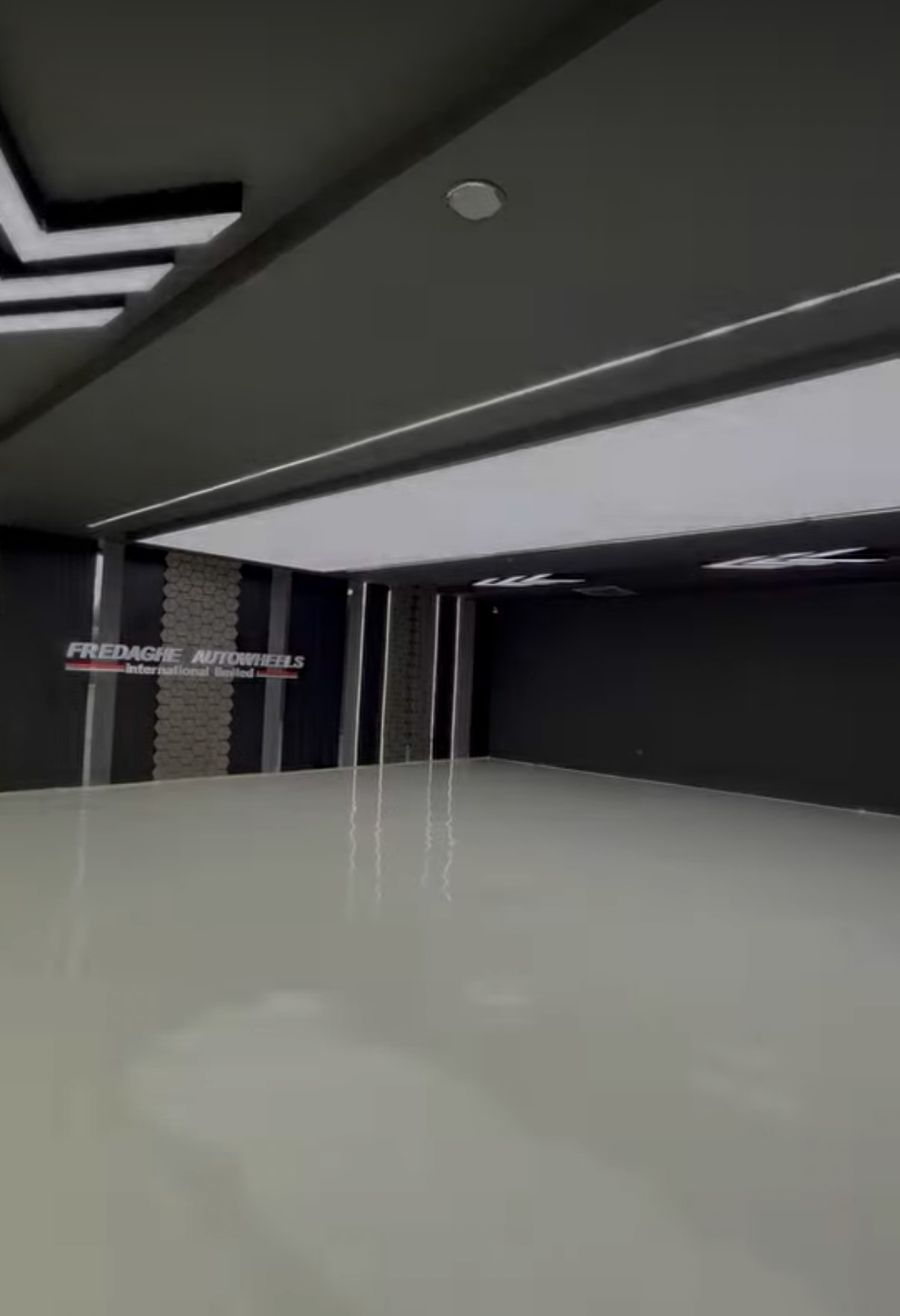 Finished car showroom with dark wall panels, hexagon feature strips, linear ceiling lights and polished floor